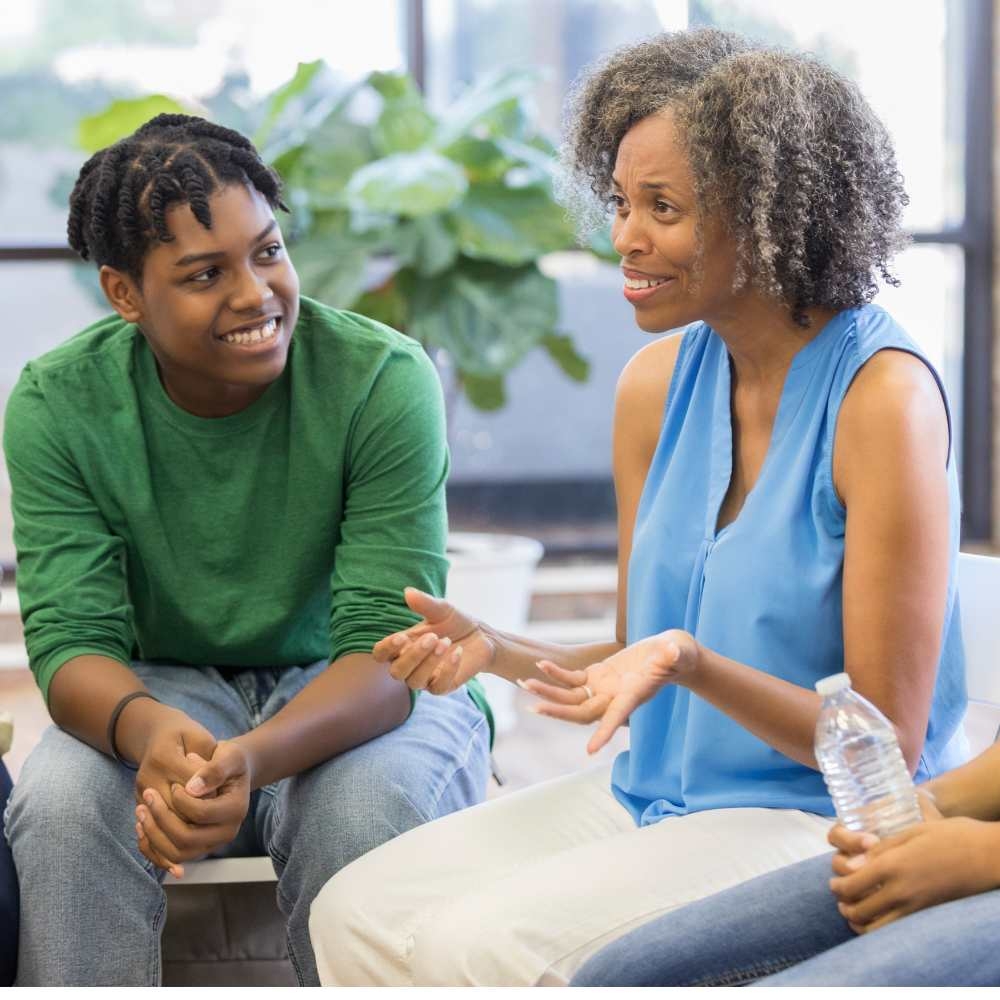 two photos one features two people who are sitting together in a support group and smiling, one features a same sex male couple and two children