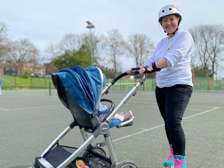 smiling lady in roller skates pushing pram