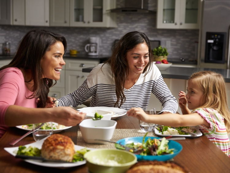 two mums and daughter eating round kitchen table