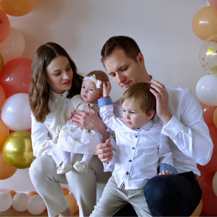 mum and dad with toddler boy and baby girl surrounded by balloons