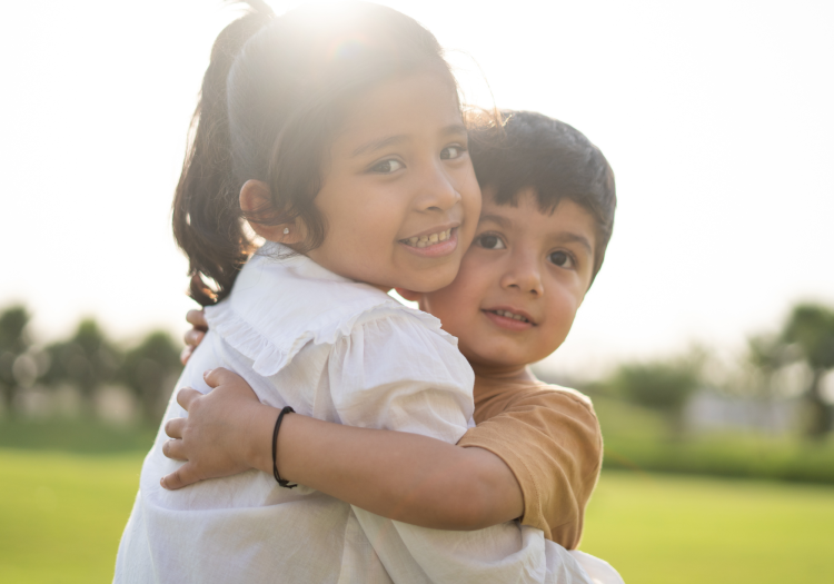 Brother and sister hugging in sunshine