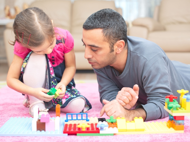 dad and daughter sitting on floor playing with blocks