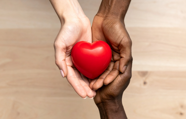 three hands with different skin tones jointly holding a heart shape
