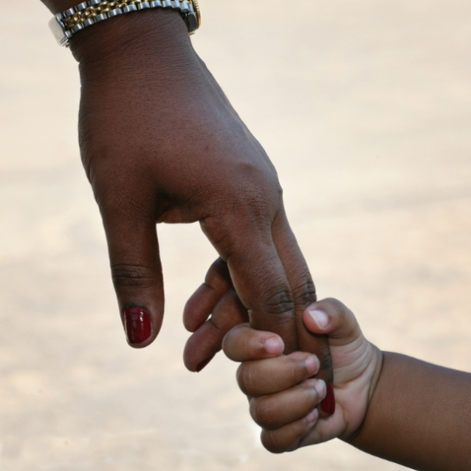 Close up of a small child's hand clinging onto a woman's fingers