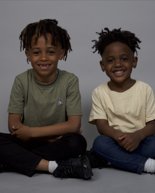 Two little brothers sitting cross legged and smiling at the camera